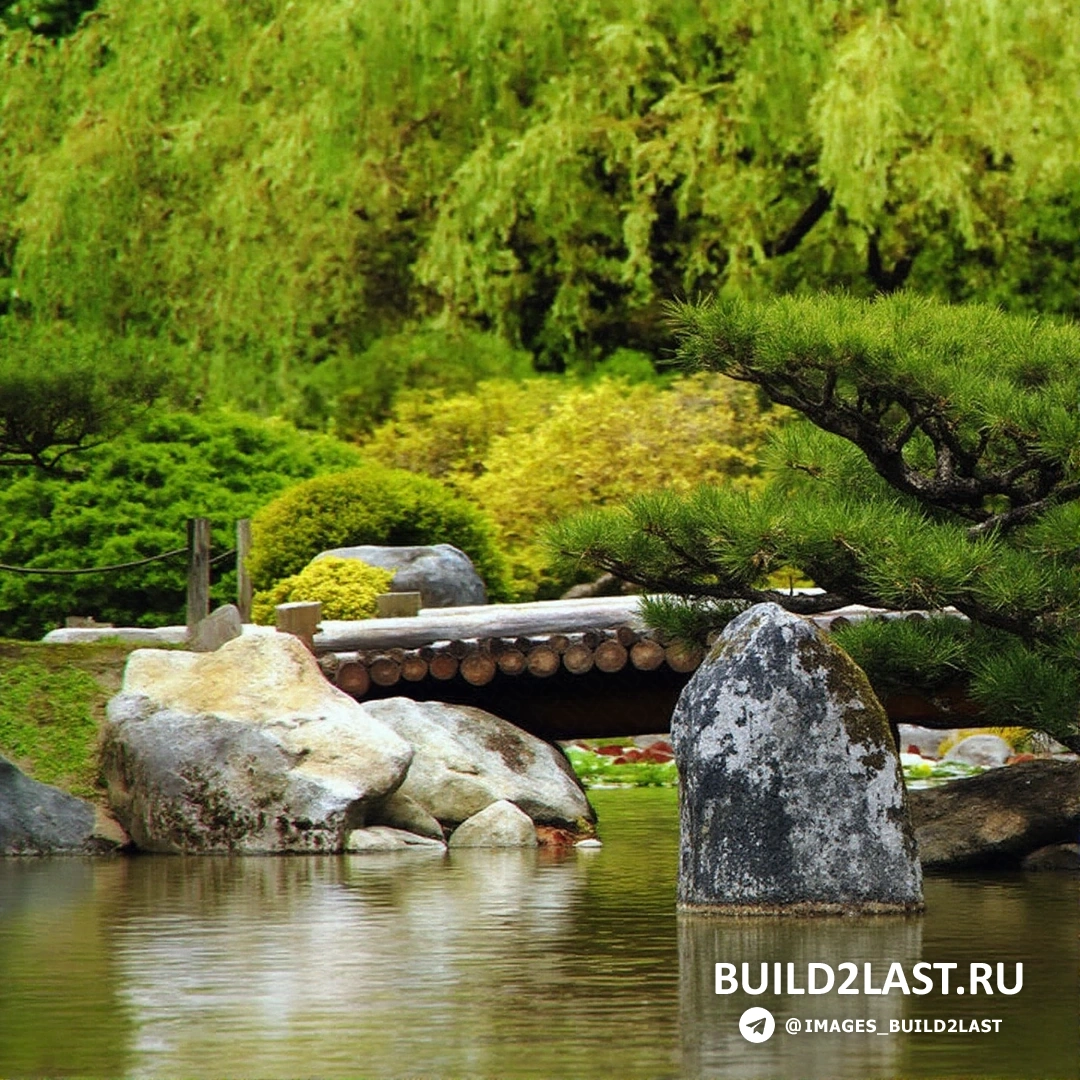 Черный и бежевый мост с коваными изделиями через искусственный водоем и тротуарную плитку